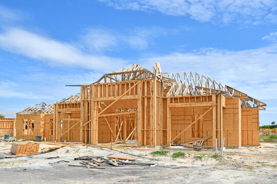 Unfinished New Single Family Residential Homes Under Construction At Wood Frame Under Blue Skies In South Florida