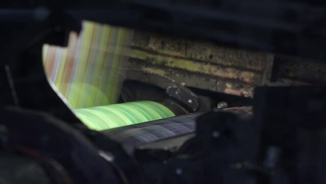 Printing house. Film spins between shafts. Roller machine prints. Shaft rotates rapidly. Anilox shafts.