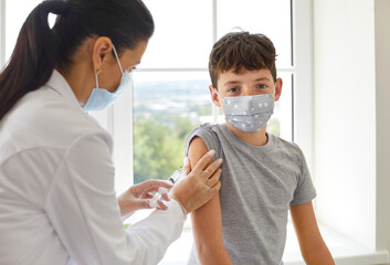 Nurse or doctor gives shoulder injection to child to protect him from dangerous pandemic. Little...
