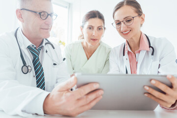 Fototapeta premium Team of doctors in meeting discussing a case looking at technology