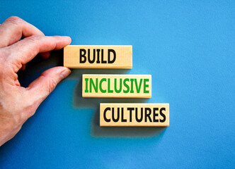Build inclusive cultures symbol. Concept words Build inclusive cultures on wooden blocks. Businessman hand. Beautiful blue background. Business build inclusive cultures concept. Copy space.