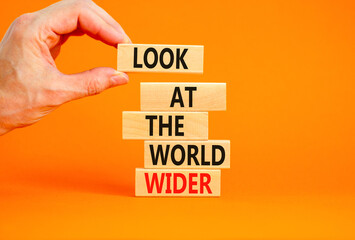 Look at the world wider symbol. Concept words Look at the world wider on wooden blocks on a beautiful orange background. Businessman hand. Business and look at the world wider concept. Copy space.