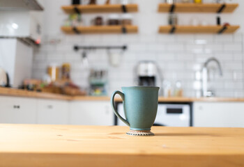 green coffee cup on kitchen table blurred kitchen in background