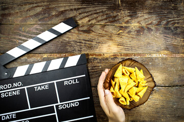clapper board of video cinema in studio and hand holding a bowl of cone corn chips in glass bowl on...