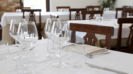 Fototapeta na wymiar Restaurant table set up with tableware and wine glass. Interior of italian restaurant