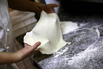Preparing Pizza dought on a marble countertops. Chef pizza maker