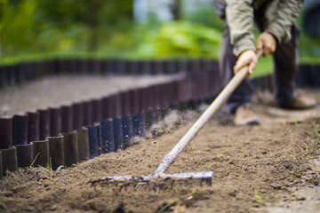 Farmer cultivating land in the garden with hand tools. Soil loosening. Gardening concept. Agricultural work on the plantation