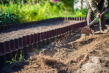 Farmer cultivating land in the garden with hand tools. Soil loosening. Gardening concept. Agricultural work on the plantation
