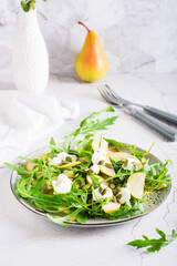 Fresh salad with pears, arugula, ricotta and pumpkin seeds on a plate. Homemade lunch. Vertical view