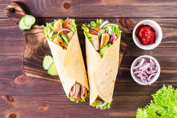Mexican tortilla wraps with chicken and vegetables on a board on the table. Top view