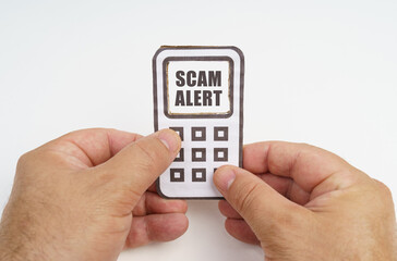 In the hands of a person is a cardboard model of a telephone with an inscription on the screen - Scam Alert