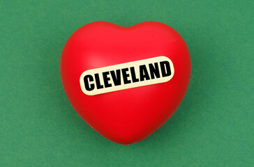 On a green surface lies a red heart with the inscription - Cleveland