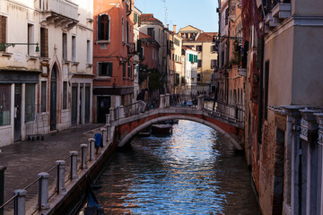 Fototapeta na wymiar The old bridge made with red bricks on the typical canal in Venice