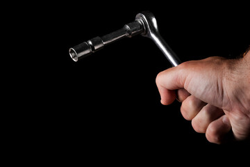 End wrench with ratchet in hand on a black background