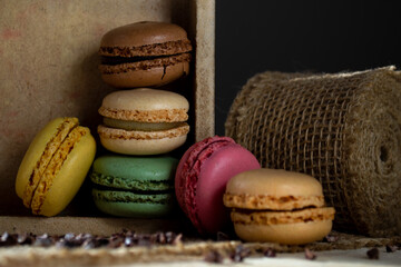 small multi-colored macaroons in a wooden box on a dark background