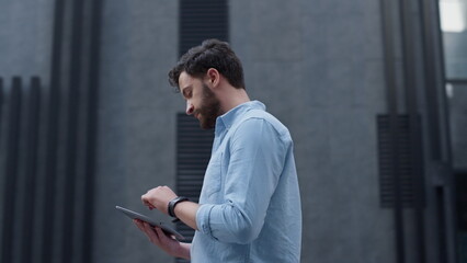 Focused manager using tablet computer at modern office building. App user.