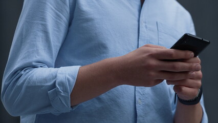 Asisstant holding smartphone texting colleagues on break. Male hands closeup.