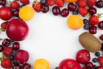 Different fruits and berries lie on a white background on the sides of the photo, forming a frame with an empty space in the middle for the text. High quality photo