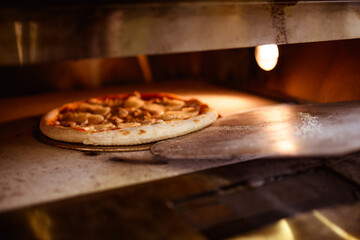 Delicious pizza baking on stone in cafe oven 