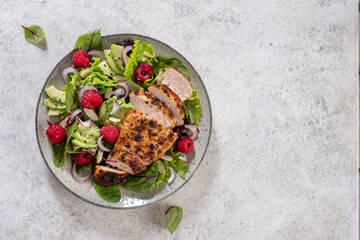Grilled chicken breast, fillet and fresh vegetable salad of lettuce, arugula, spinach, avocado, onion and pecan nut with raspberry. Summer salad, healthy eating. Fresh healthy food.