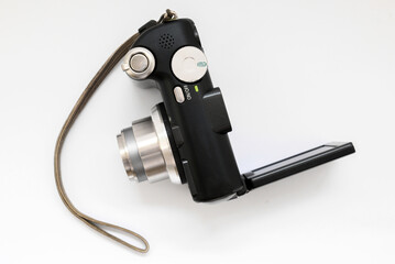 compact digital camera in black with a gray zoom lens and a rotary display on a white background close-up