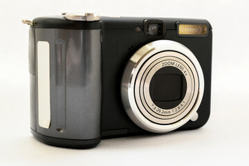 compact digital camera in black with a gray zoom lens on a white background close-up