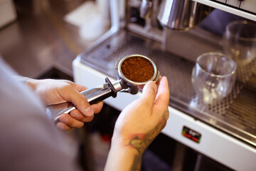 Partial view of barista holding machine holder with fresh coffee 
