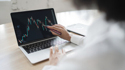 Fototapeta na wymiar Job trader sells stocks on the stock exchange online chart, uses a laptop