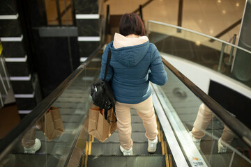Fototapeta na wymiar Girl in shopping mall on lift. Girl on stairs. Interior of office building.