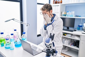 Young man scientist stressed using laptop working at laboratory