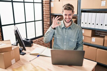 Hispanic man with beard working at small business ecommerce doing ok sign with fingers, smiling friendly gesturing excellent symbol