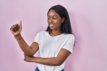 African young woman wearing casual white t shirt looking proud, smiling doing thumbs up gesture to the side