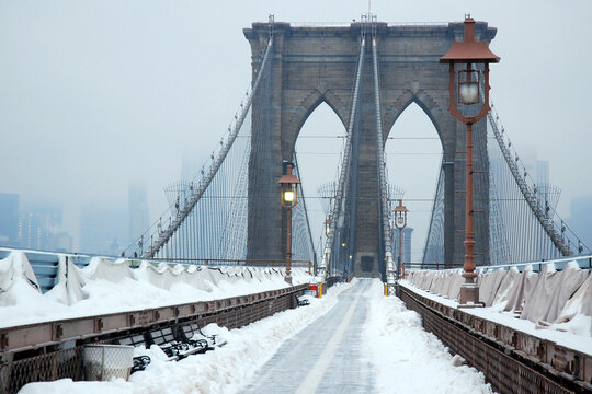 A path is cleared on the pedestrian walkway of the Brooklyn Bridge during a snow storm - Powered by Adobe