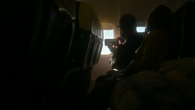 A man taking a picture with his phone of the skyview in an airplane trip.