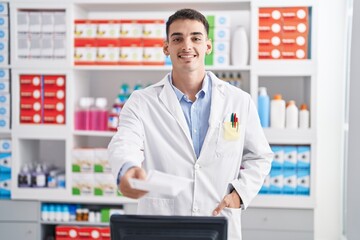 Young hispanic man pharmacist smiling confident holding prescription at pharmacy