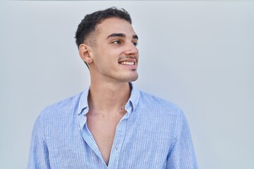 Young hispanic man smiling confident looking to the side over white isolated background