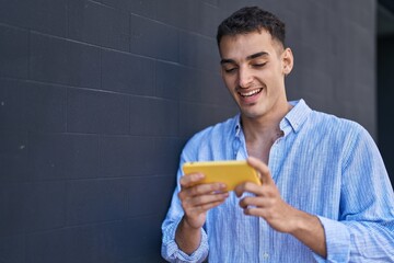 Young hispanic man smiling confident watching video on smartphone over black isolated background