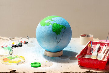 hand-painted globe of the world, with brushes and colored paint. image with horizontal copyspace
