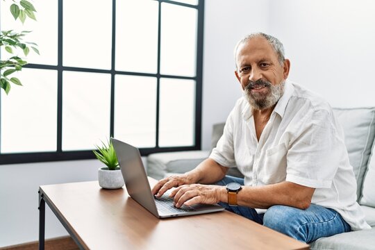 Senior grey-haired man smiling confident using laptop at home