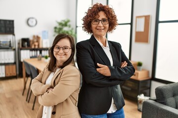 Group of two women working at the office. Mature woman and down syndrome girl working at inclusive teamwork.