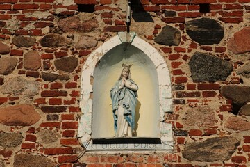 Figurka Maryi umieszczona w ceglanej fasadzie