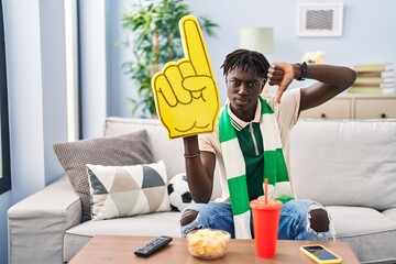 African man with dreadlocks football hooligan supporting team with angry face, negative sign showing dislike with thumbs down, rejection concept