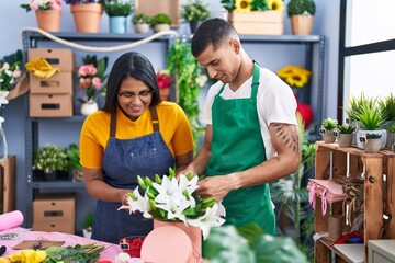 Man and woman florists smiling confident making bouquet of flowers at florist