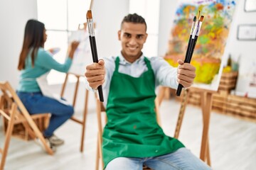 Young latin painter couple smiling happy painting at art studio