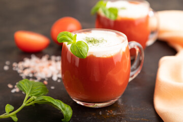 Tomato juice with basil and himalayan salt in glass on a black background. Side view, selective focus.