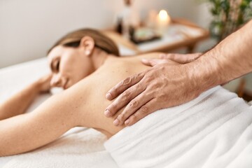 Woman smiling happy reciving back massage at beauty center.