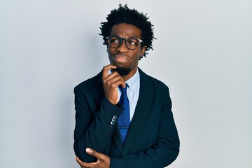 Young african american man wearing business suit serious face thinking about question with hand on chin, thoughtful about confusing idea