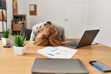 Middle age businesswoman overworked with head on desk at the office.