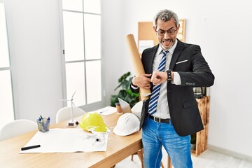 Middle age hispanic business man holding paper blueprints looking at the watch time worried, afraid of getting late