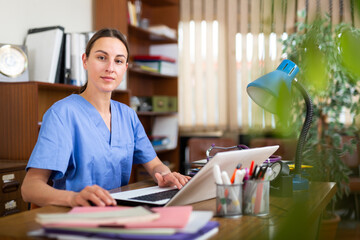 Young female therapist working in a medical clinic is sitting at her workplace in the resident's office at a computer